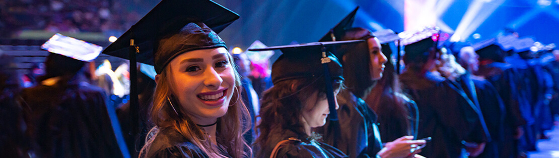 Smiling female student in cap and gown at PCC graduation