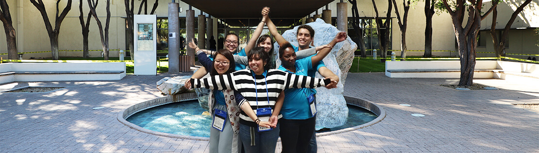 Connect U Students stand in front of the fountain at Pima's Downtown campus posing