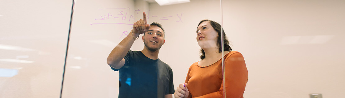 a student tutor assists a student with a math equation in a Pima study room