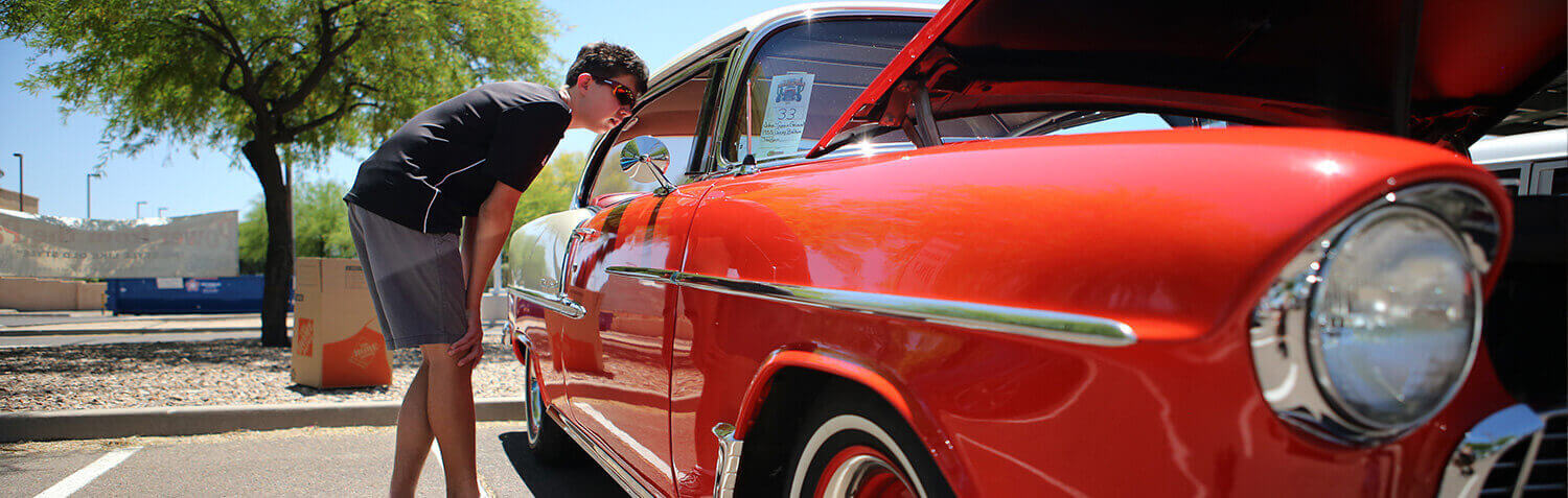 A Teen looks inside an old cherry red hot rod