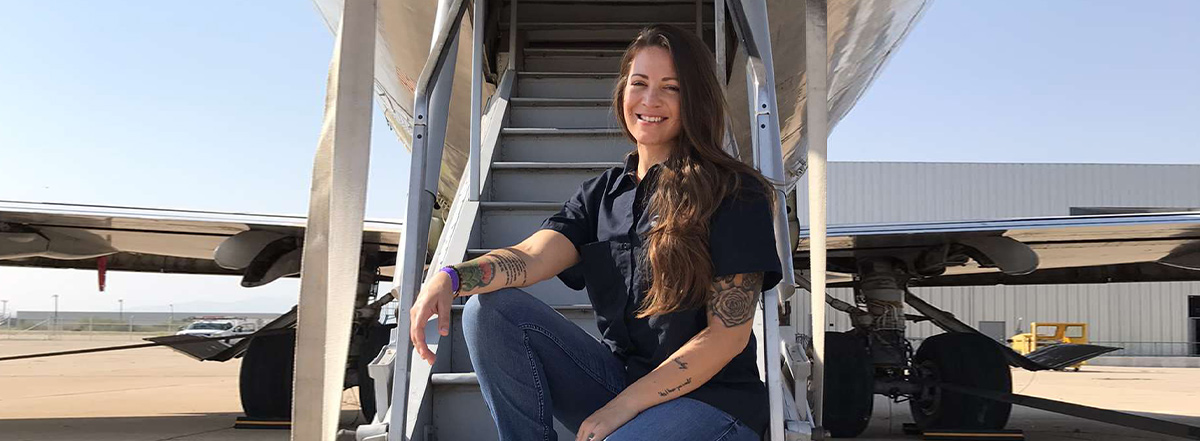 Image of Aviation student, Kathryn Pena sitting on the rear stairs of a aircraft