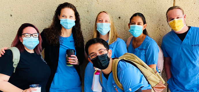 Nursing students smile in blue masks and scrubs.