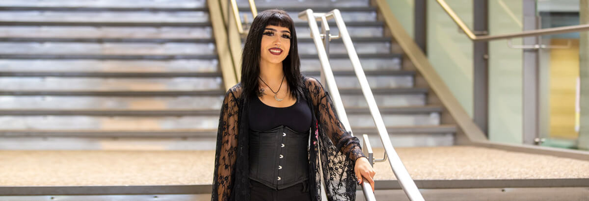 Maleah Manning stands smiling on a staircase at Pima's West Campus