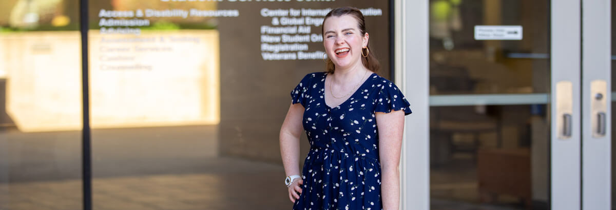 Alexis Rose Young stands smiling in front of the Student Service Center at Pima's West Campus