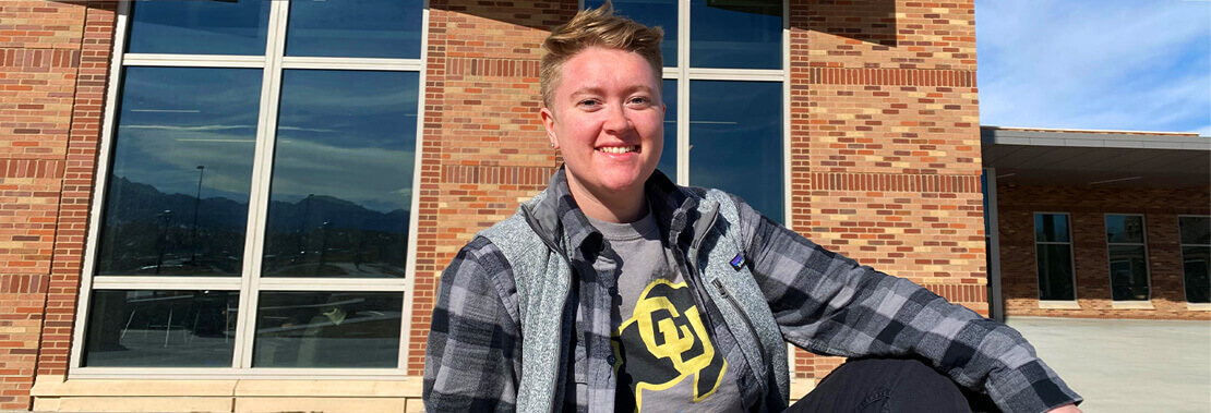 Liz Graybill sits smiling in front of a brick building