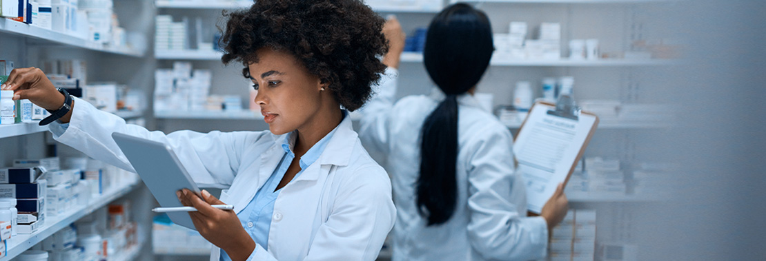 A woman looks through medication while comparing to a tabletin a hospital medication room