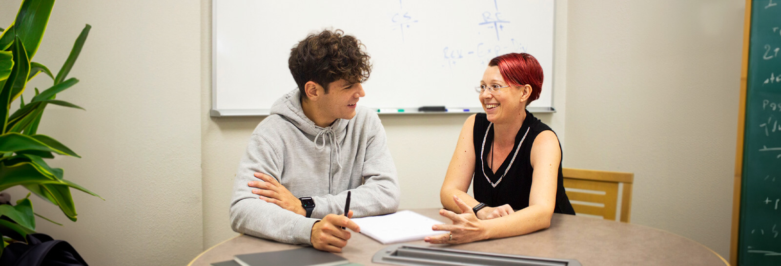 Samantha Overton sits at a table in a study room with a student studying