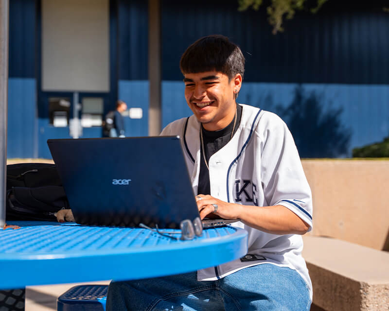 Student sitting outdoors on a Pima campus.