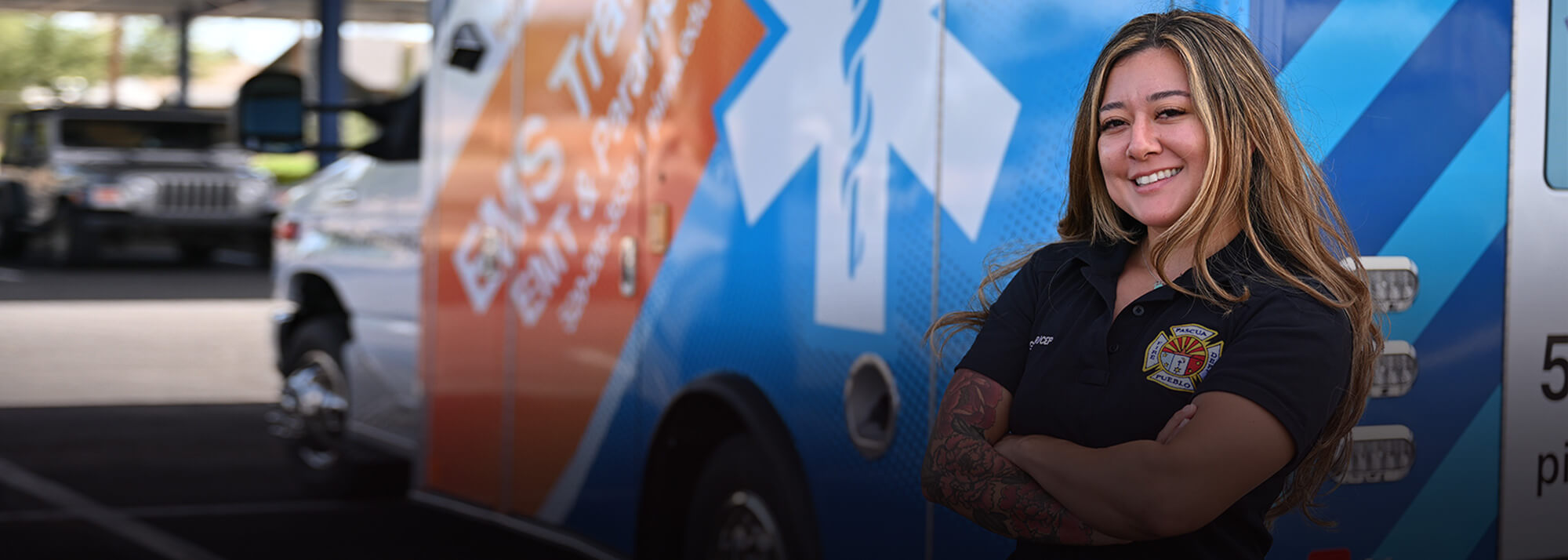 A student poses next to a van with Pima Community College branding.