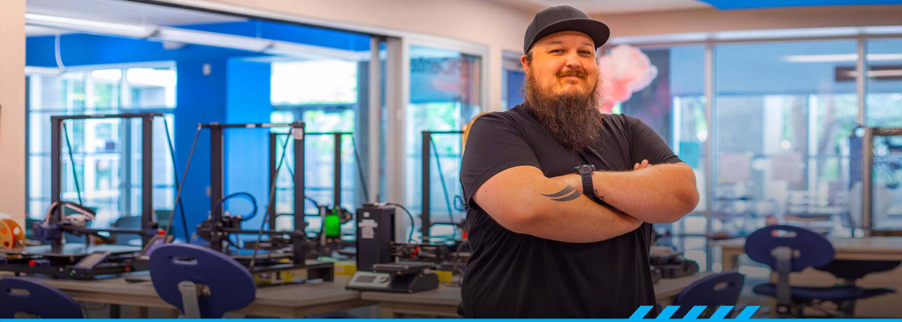 Marc Vaughn stands arms crossed with a grin in the Makerspace at East Campus