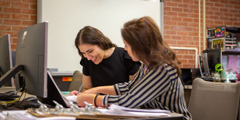 Two female students work together in a Pima computer lab.