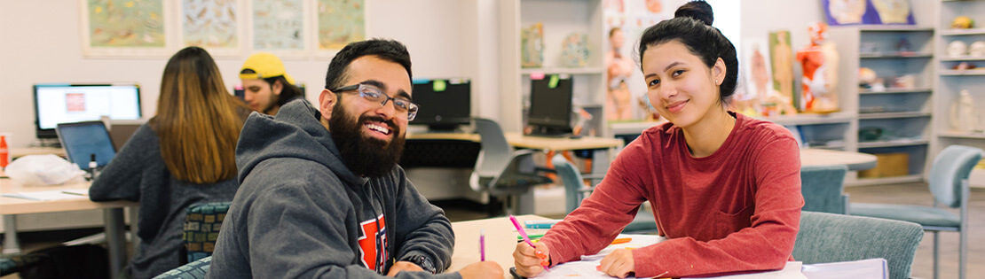 A tutor and student smile for the camera at a PCC library.