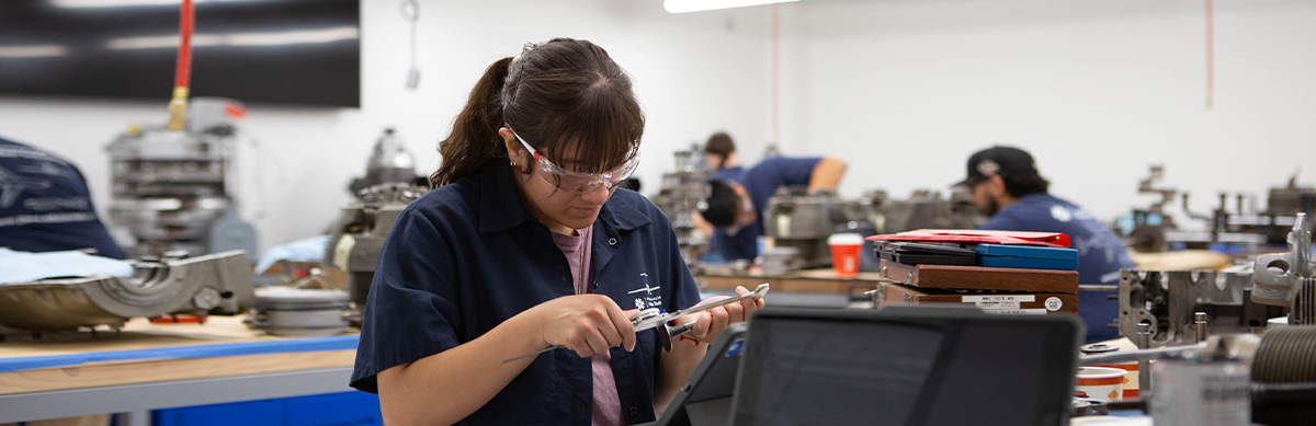 An aviation student works on a device inside an aviation classroom