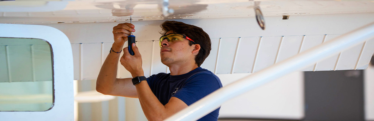 An aviation student works on the airframe of a plane