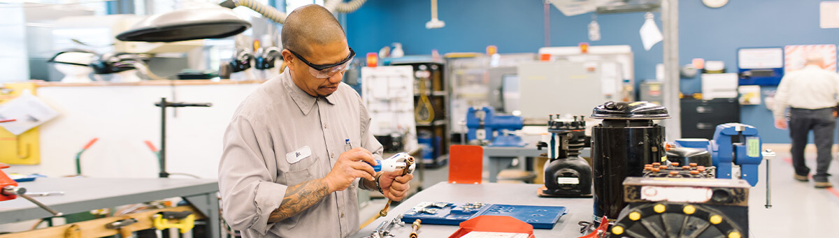 A student works on manufacturing equipment in a Pima Lan