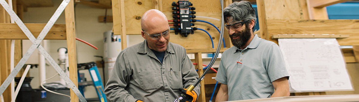 two students work on plumbing equipment in a Pima Lab