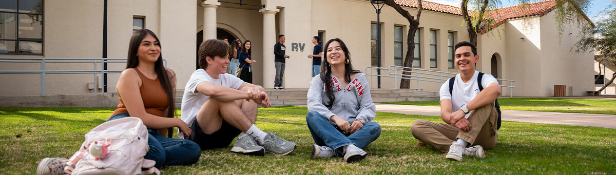 A group of students  sit smiling on a Pima campus 