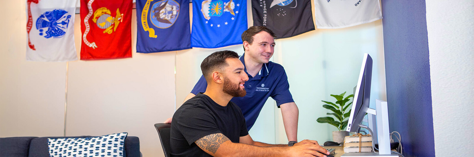 A veteran student works in a veteran services center with the help of a Staff member