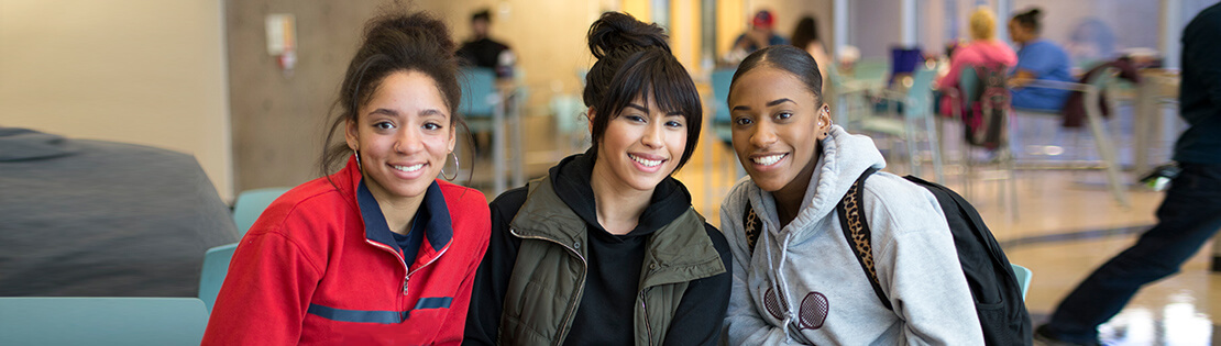 three students sit in a Pima Campus student lounge smiling 