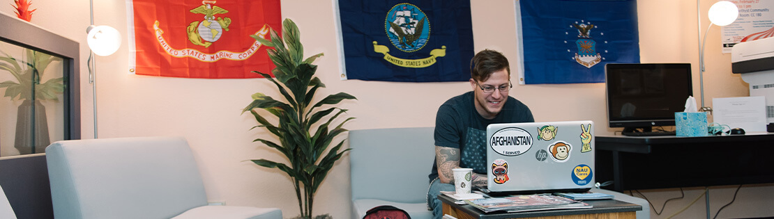 A veteran student sits smiling inside of a veterans center at a Pima campus