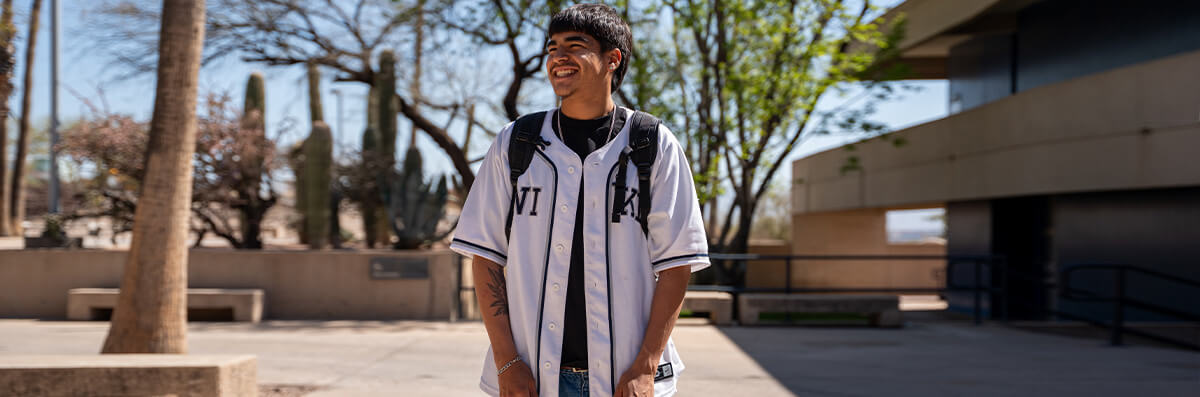 A pima student walks smiling at West Campus.