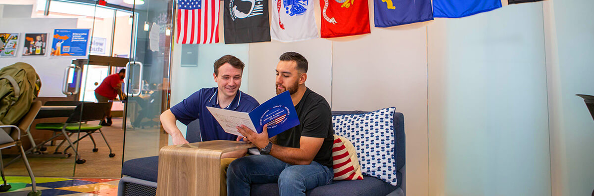 A veteran student works in a veteran services center with the help of a Staff member