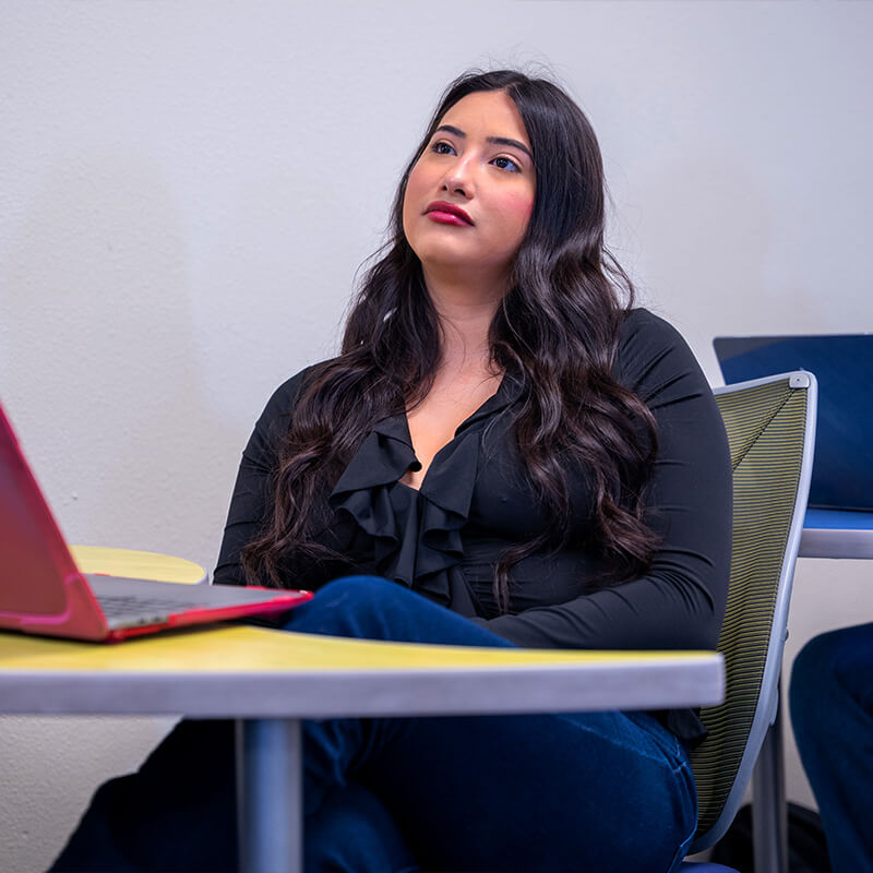 Yazmin sits in a class with a computer