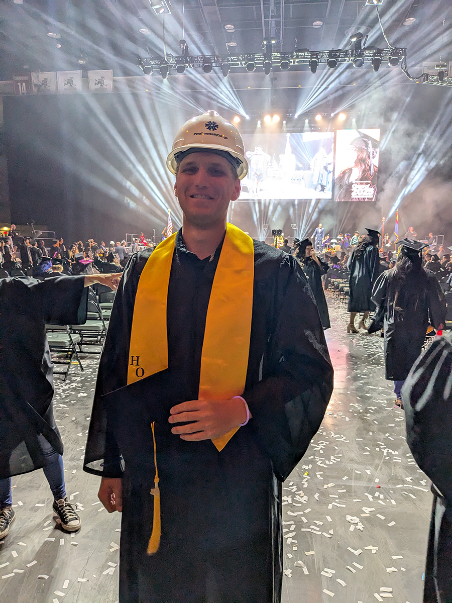 Beau Bidwell Stands in his graduation robes at commencement